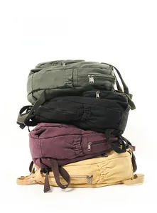 Vertical stack of canvas backpacks in army green, black, burgundy, and mustard yellow colors