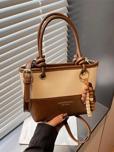 Chic two-tone handbag in cream and brown leather with beaded charm and crossbody strap