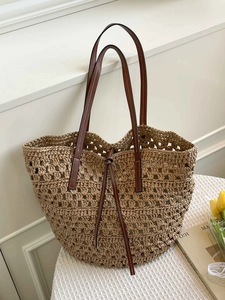 Handwoven straw tote bag with brown leather straps and cutout design for beach or commute