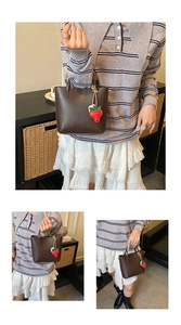 Dettaglio borsa a secchiello marrone scuro con ciondolo a forma di fragola rossa creativa