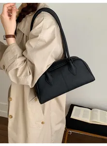 Chic black matte leather Boston bag styled with a beige trench coat for a minimalist look