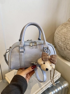 Minimalist light blue Boston bag with plush bear charm on stylish vintage books
