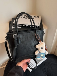 Chic black faux leather bucket bag with top handles and cute bear charm pendant