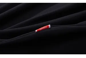Detail of black cotton fabric texture with a red rectangular 'FASHION' label on T-shirt