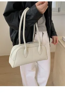 Detailed view of creamy white leather bowling bag with stylish long handles for shoulder wear