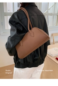 Brown leather bowling bag shown on model for size perspective in a studio setting