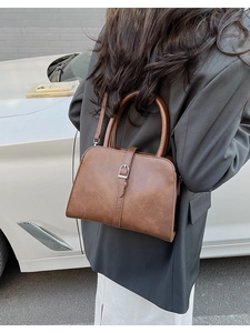 Sac à main marron vintage avec détail de boucle porté par un mannequin en tenue décontractée