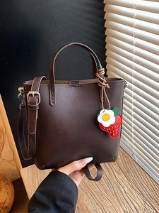 Borsa a secchiello marrone cioccolato minimalista con ciondolo fragola e tracolla