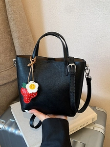 Borsa a secchiello nera minimalista con ciondolo a fragola e tracolla regolabile