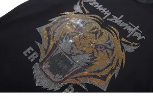 Gros plan du motif tigre étincelant en strass colorés sur un t-shirt noir en coton