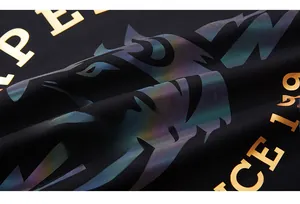 Detailed macro view of colorful laser wolf head print and gold lettering on black knit fabric