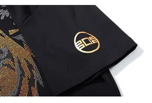 Détail d'un t-shirt noir en coton avec des strass de tigre et logo doré imprimé dessus