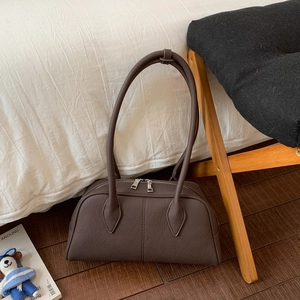 Detailed macro view of dark brown retro pillow bag with silver metal zipper on white bedding