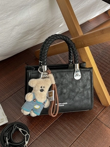 Minimalist black faux leather tote bag with woven handles and cute bear charm