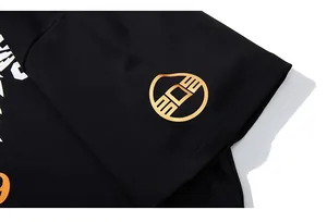 Macro shot of sleeve cuff with gold metallic logo and orange print on black heavy cotton T-shirt