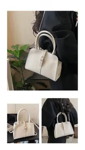 Detail showing creamy white textured leather handbag with buckle strap and round handles