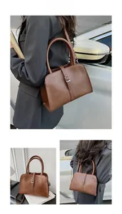 Detail shot of vintage brown satchel featuring cylindrical handles and metallic buckle
