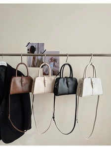 Retro leather handbags in brown, beige, black and white hanging from a metal rod