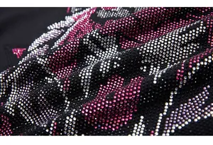 Macro shot of detailed pink and silver rhinestone patterns on black fabric texture
