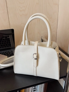 Sac à main structuré crème avec boucle en D argentée posé sur un bureau de bureau