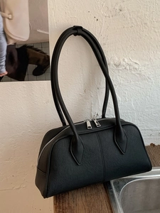 Retro black pebble leather bowling handbag with double handles and zip closure on wood table