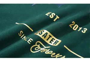 Detalle de sudadera verde con letras gráficas premium en tonos dorados e irisados