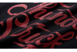 Macro shot of red glitter 'Good Luck' lettering on black knit fabric with luxury texture