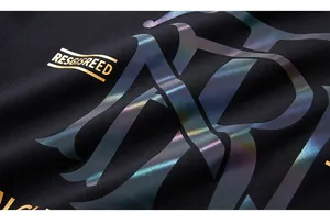 Macro detail of holographic reflective print and gold lettering on black thermal tee