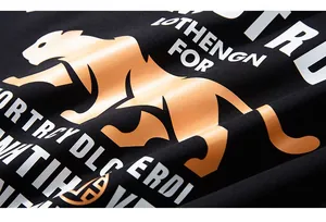 Close-up of golden leopard print and typography on black long-sleeve knit shirt fabric