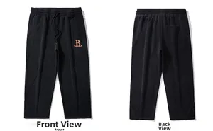 Détail recto-verso du pantalon de jogging noir avec broderie lettre B orange