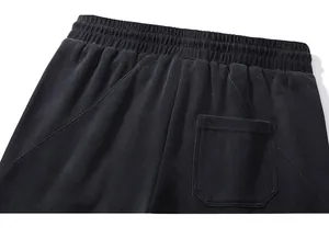 Detail of black sports trousers featuring an elastic waistband and stitched patch pocket