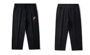 Detail view showing black sports trousers with elastic waist and white embroidered letter