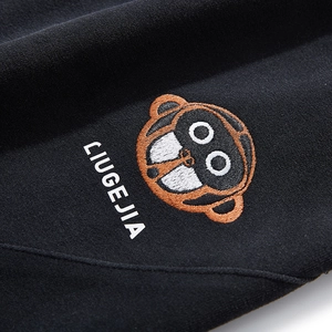 Detail of premium embroidery on black raglan hoodie featuring a cartoon monkey logo