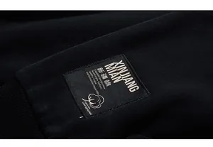 Detailed view of the ribbed cuff and embroidered cotton origin label on the black hoodie
