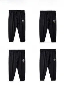 Détail de quatre joggings noirs pour hommes avec taille élastique et broderie zodiacale