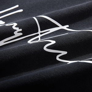 Close-up of black oversized hoodie featuring white cursive graphic print and knit texture
