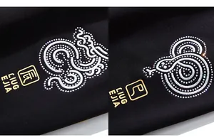Détail de broderie dragon avec strass et logo en feuille d'or sur un pantalon de jogging