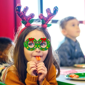 Girl wearing festive sequin reindeer headband and Christmas wreath glasses for party