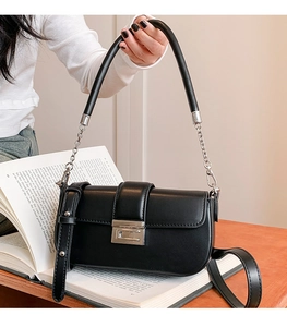 Close-up of black glossy leather bag featuring silver buckle and chain handle detail