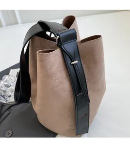 Détail de la bandoulière réglable en cuir noir et des ferrures d'un sac seau marron