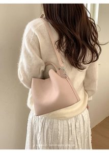 Detail of pink pebbled leather bucket bag with silver metal buckle on shoulder strap