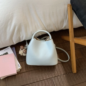 Detail of light blue bucket bag with pebble leather texture and cute floral bear charm