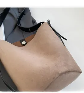 Gros plan sur un sac seau mat en daim marron avec détails de bandoulière en cuir noir