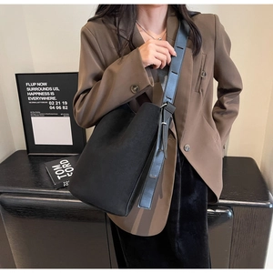 Détail du sac seau en daim noir avec bandoulière en cuir et boucle en métal argenté