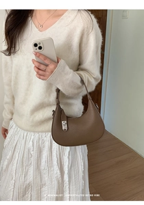 Braune Halbmond-Tasche aus Narbenleder am Modell im minimalistischen Retro-Design