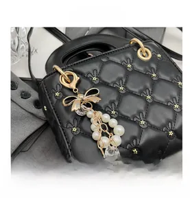 Detail of black quilted handbag with gold stars and elegant pearl bow charm