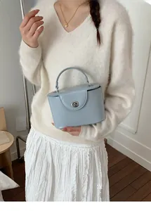 Close-up of a light blue structured box bag with a silver swivel clasp on a model