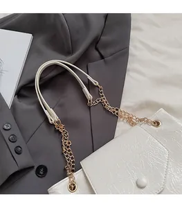 Détail du sac en cuir plissé blanc avec bandoulière chaîne dorée sur blazer gris