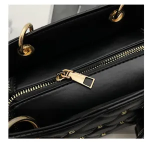 Close-up of smooth gold zipper and quilted leather detail on the black handbag