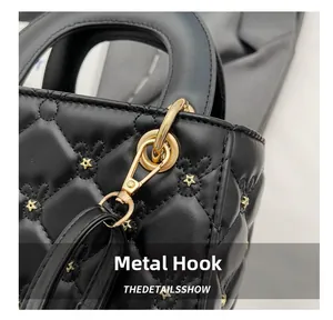 Detail of black quilted bag with gold star embroidery and polished hardware